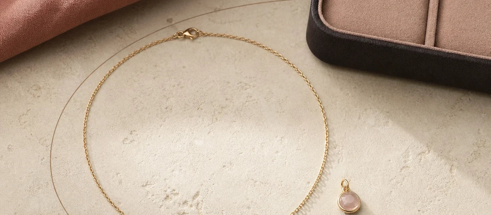 Wide flatlay of a Miorava necklace and matching one-cat Bond Charm