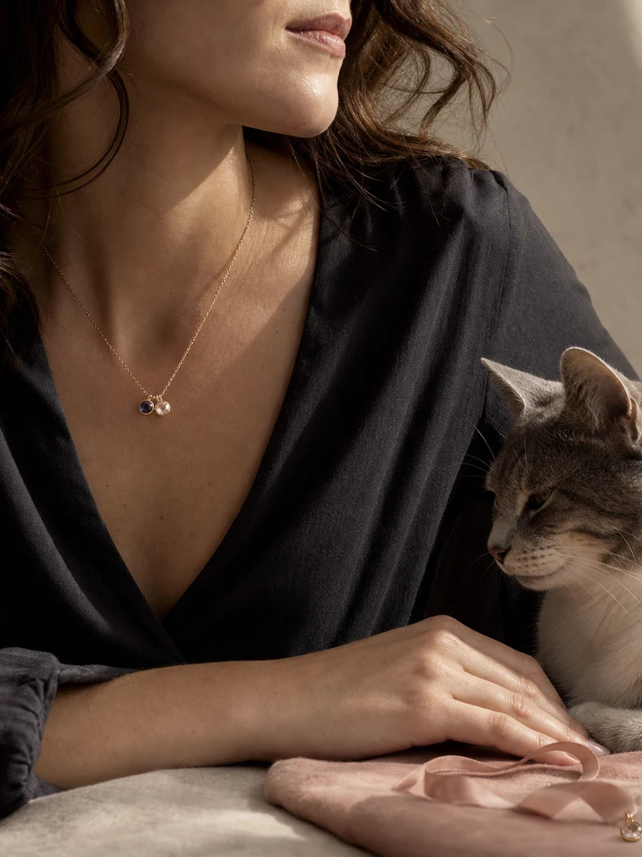 Cat owner wearing a symbolic two-stone birth month necklace