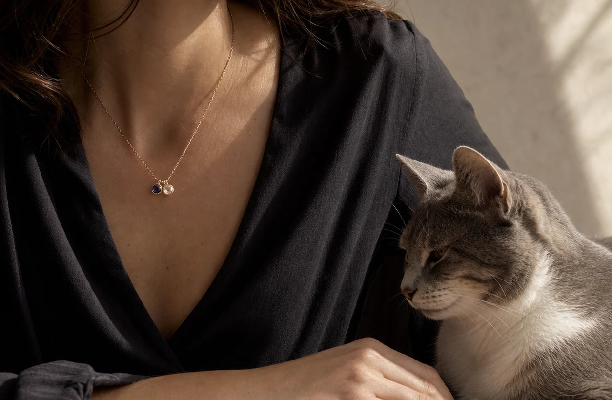 Woman wearing a two-stone relationship necklace beside her cat