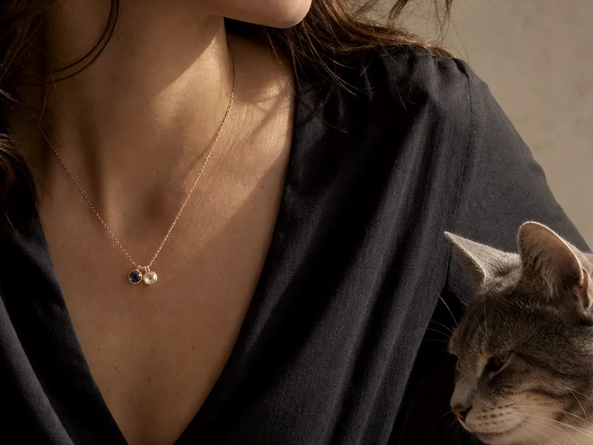 Woman wearing a two-birthstone Miorava necklace beside her cat